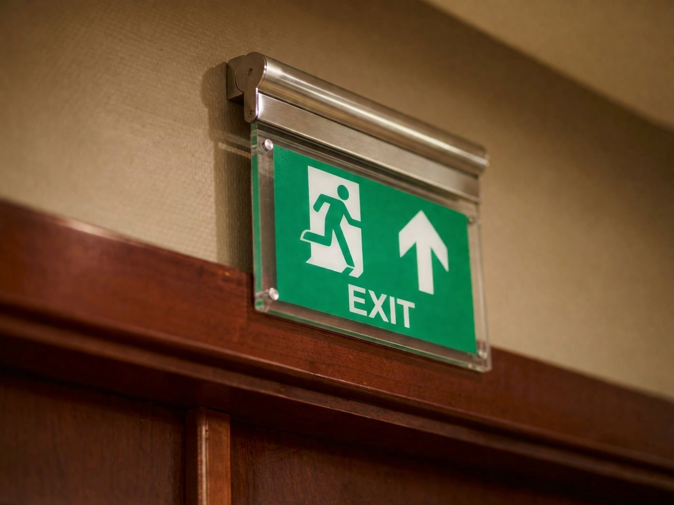 Une enseigne de secours verte moderne avec un cadre en acier inoxydable brossé, affichant un pictogramme d'homme qui court vers la droite, une flèche pointant vers le haut et l'inscription 